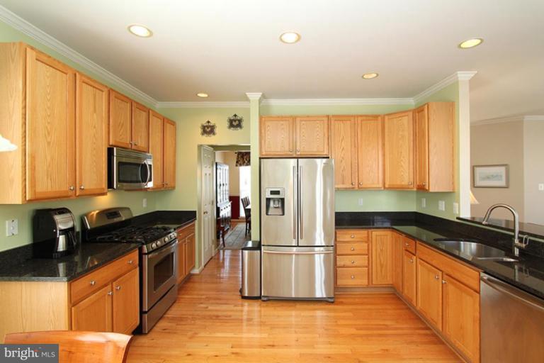 18409 Cornflower Road Boyds, MD 20841 - Photo 5 of 24 a kitchen with granite countertop a refrigerator a sink a stove top oven and cabinets