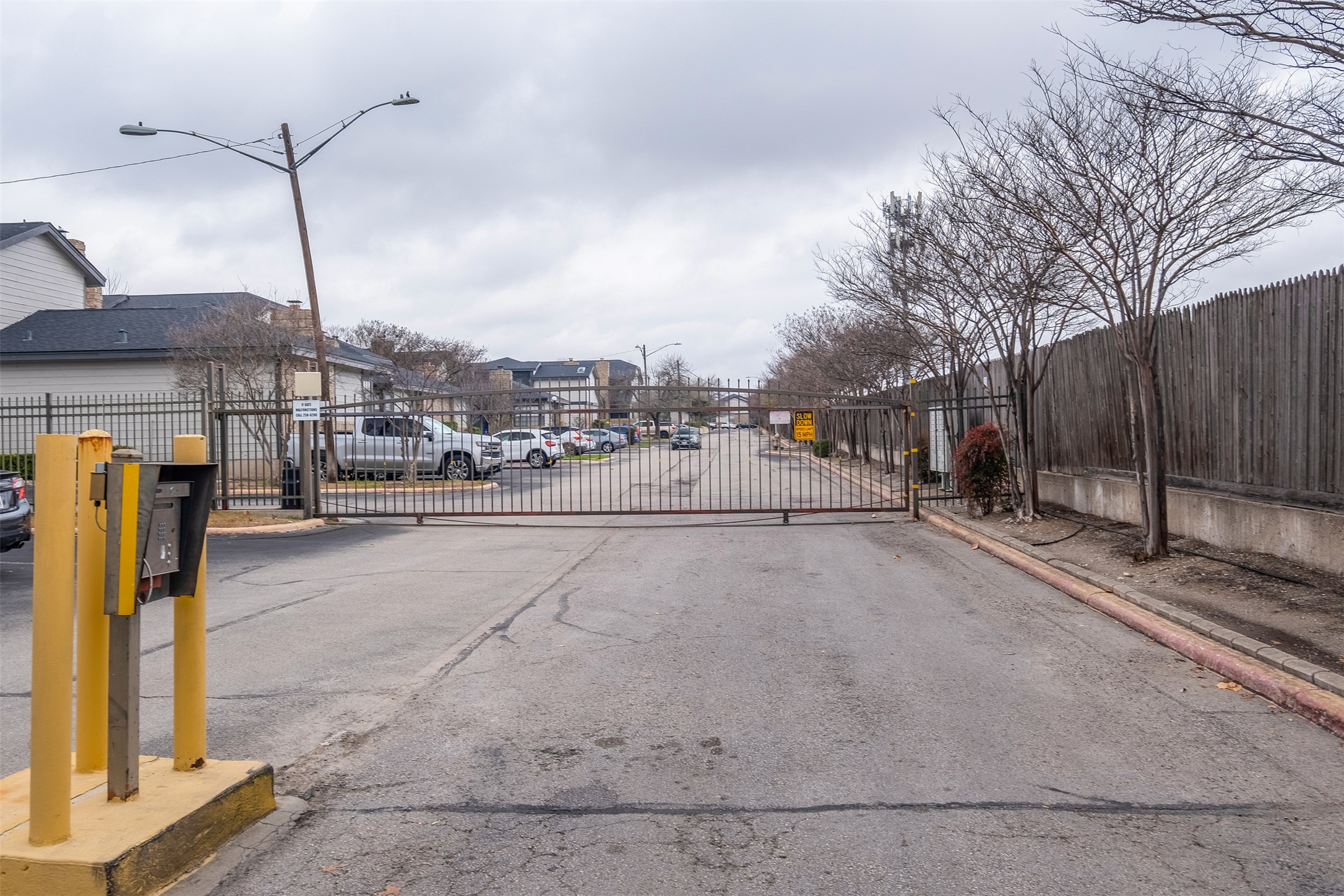 1748 Ohlen Road, Unit 16 Austin, TX 78757 - Photo 34 of 38 View of asphalt road featuring street lighting, a gated entry, curbs, and a gate