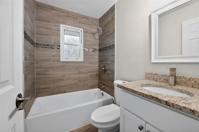a bathroom with a granite countertop sink toilet and bathtub