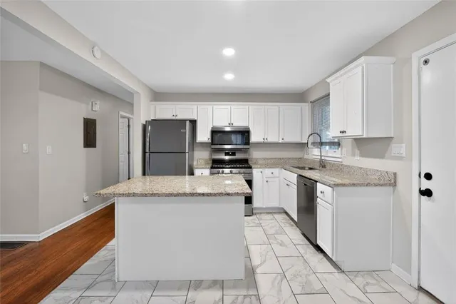 a kitchen with granite countertop a sink stainless steel appliances and white cabinets