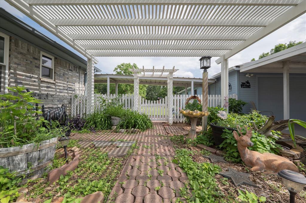 107 Fort Graham Circle Waco, TX 76705 - Photo 3 of 39 Pergola-covered brick-paver pathway leading to a white picket fence gate