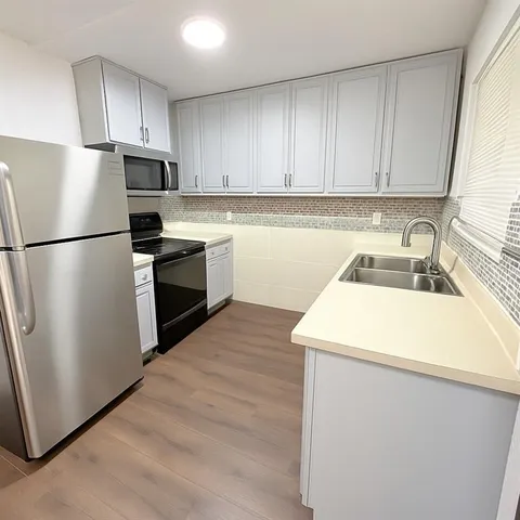 a kitchen with a sink a refrigerator and cabinets