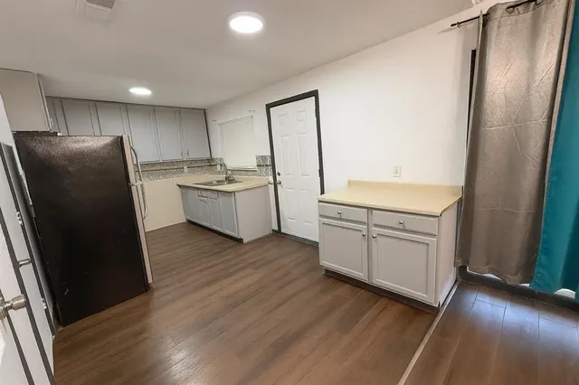 a kitchen with a sink a refrigerator freezer a stove top oven a counter space and wooden floor