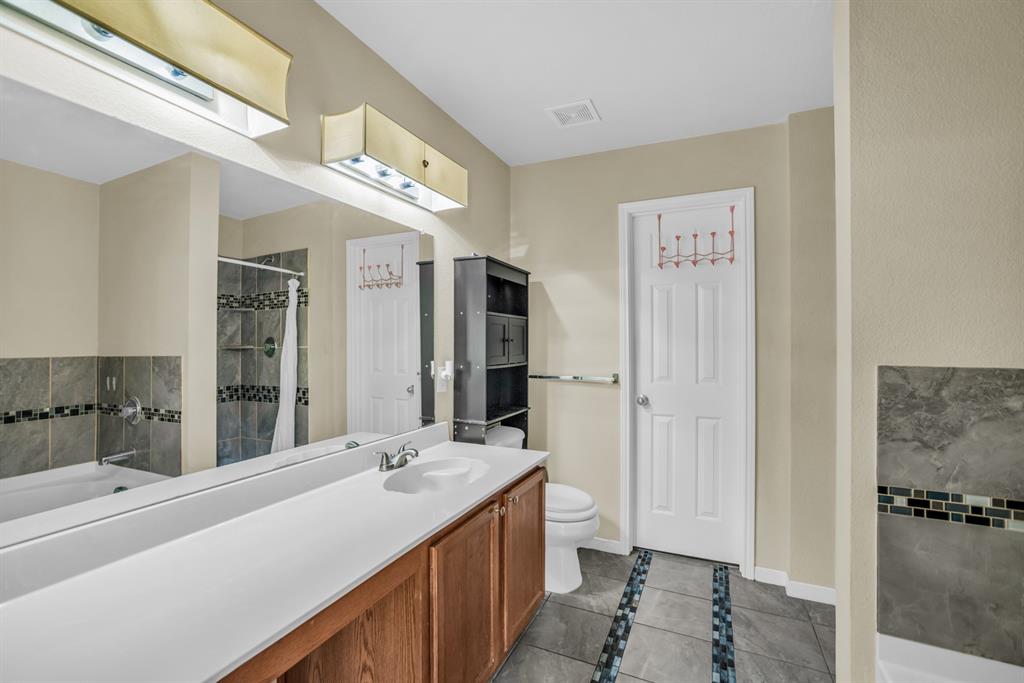 5718 Green Ivy Road Denton, TX 76210 - Photo 18 of 37 Double vanity with a white countertop and wood-finish cabinetry