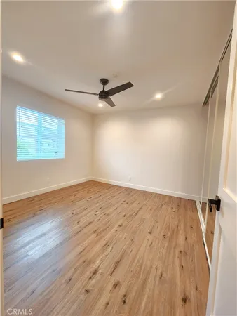 an empty room with wooden floor fan and windows