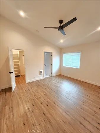 a view of empty room with wooden floor and fan