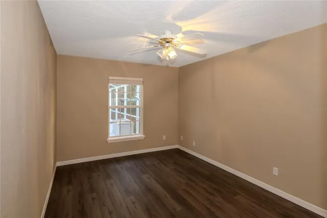 an empty room with wooden floor and chandelier fan