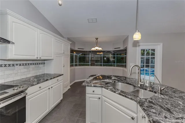 a kitchen with kitchen island granite countertop a stove and a sink