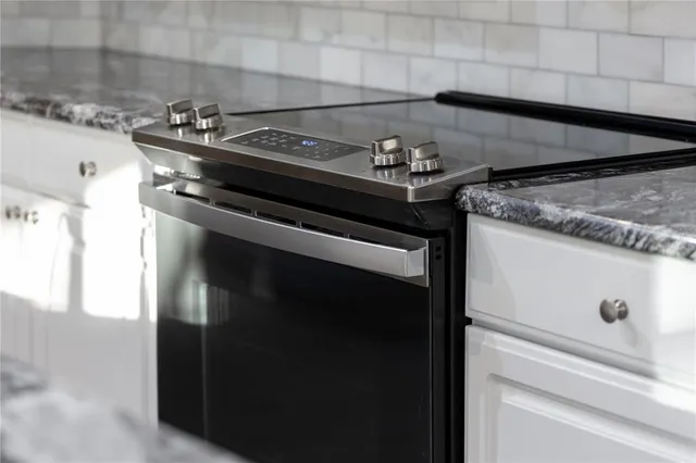 a kitchen with granite countertop a sink a stove and cabinets