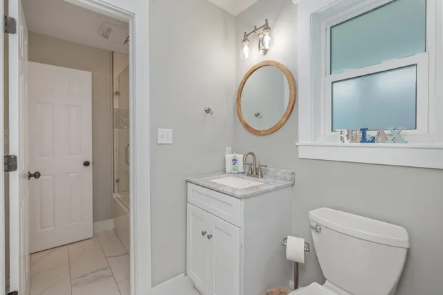 a bathroom with a toilet a sink a mirror and vanity