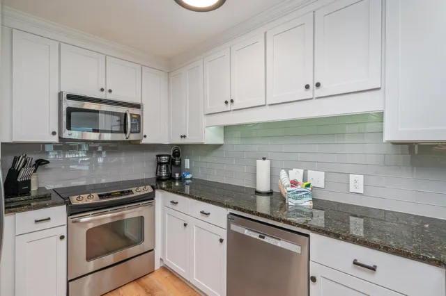 a kitchen with stainless steel appliances granite countertop white cabinets a sink and dishwasher