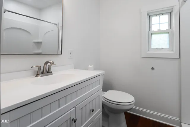 a bathroom with a toilet a sink and mirror
