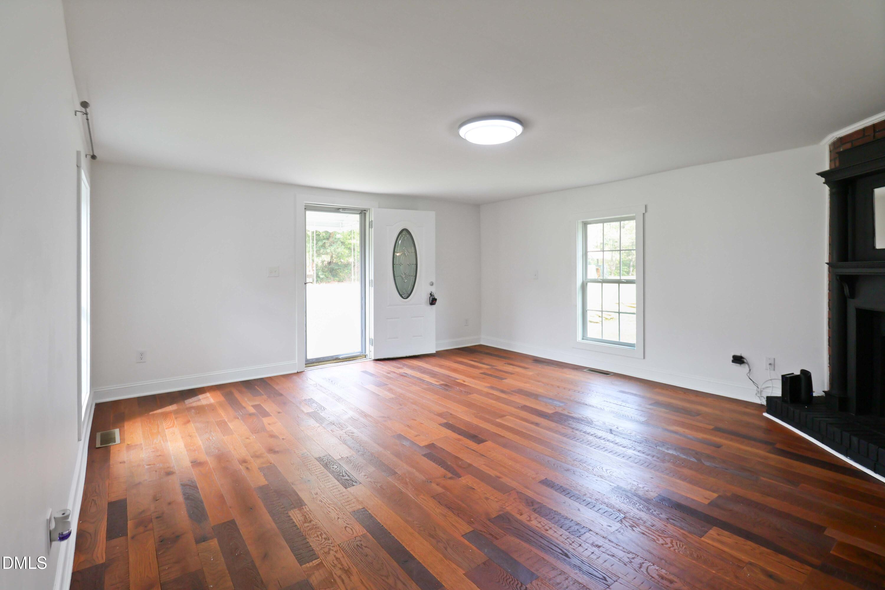 5209 Durham Road Raleigh, NC 27613 - Photo 4 of 18 an empty room with wooden floor and windows