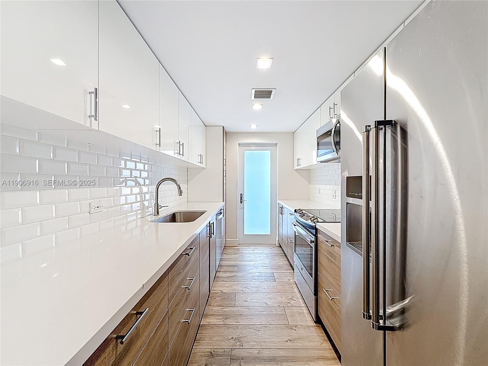 254 Seaview Drive, Unit 5 Key Biscayne, FL 33149 - Photo 13 of 30 a kitchen with white cabinets and stainless steel appliances