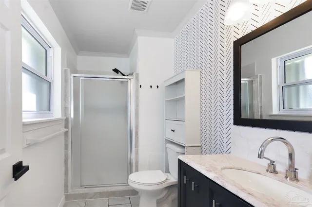 a bathroom with a granite countertop sink toilet a mirror and shower