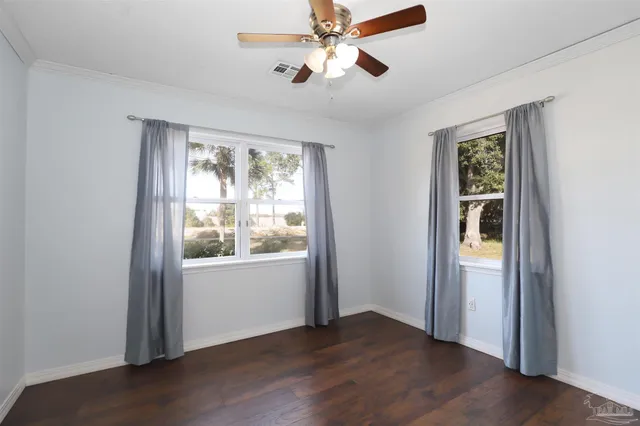 a view of an empty room with a window and wooden floor