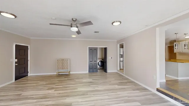 a view of a livingroom with a chandelier fan and wooden floor