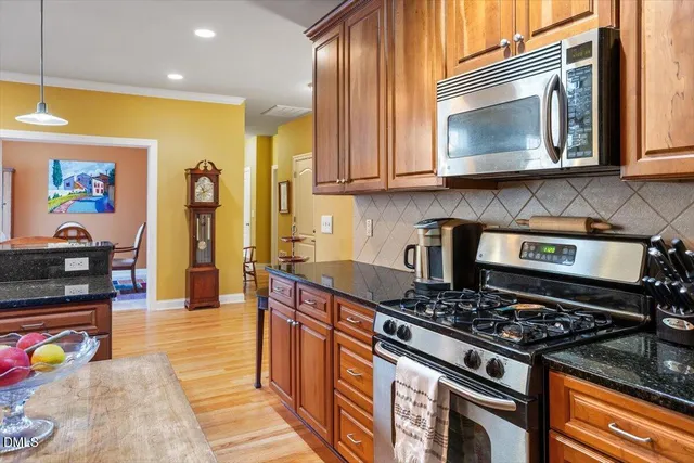 a kitchen with stainless steel appliances granite countertop a stove a sink and a microwave