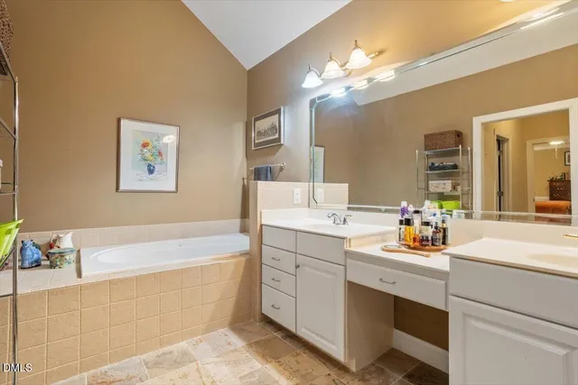 a bathroom with a tub a sink double vanity and a mirror