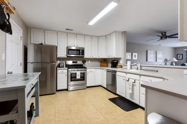 a kitchen with a sink white cabinets and stainless steel appliances