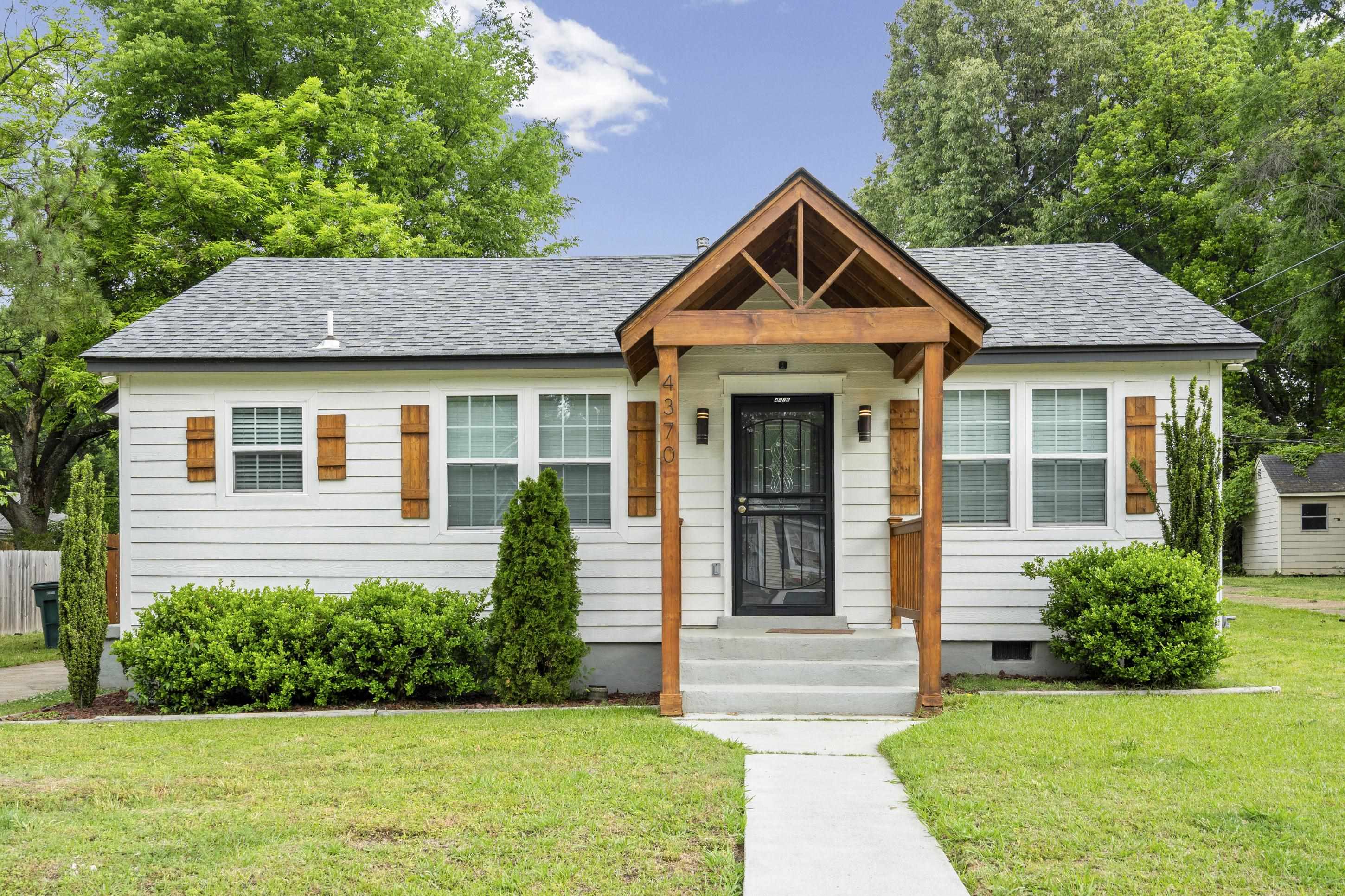 White siding exterior featuring a natural wood-finish front porch with exposed beams, a black security screen door, and matching wood-finish window shutters