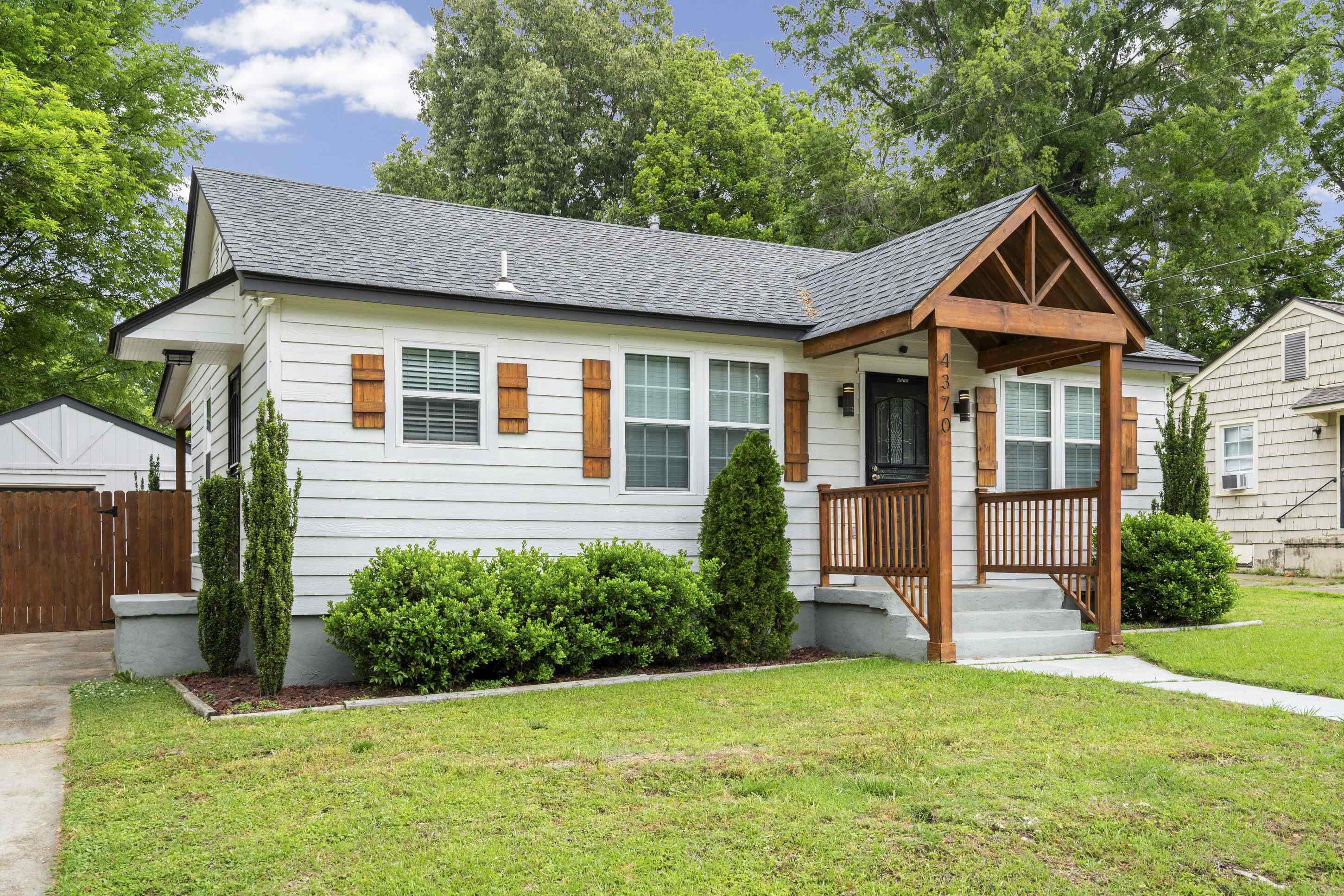 4370 Given Avenue Memphis, TN 38122 - Photo 22 of 30 White siding exterior with a prominent gabled front porch featuring dark wood architectural details and railing