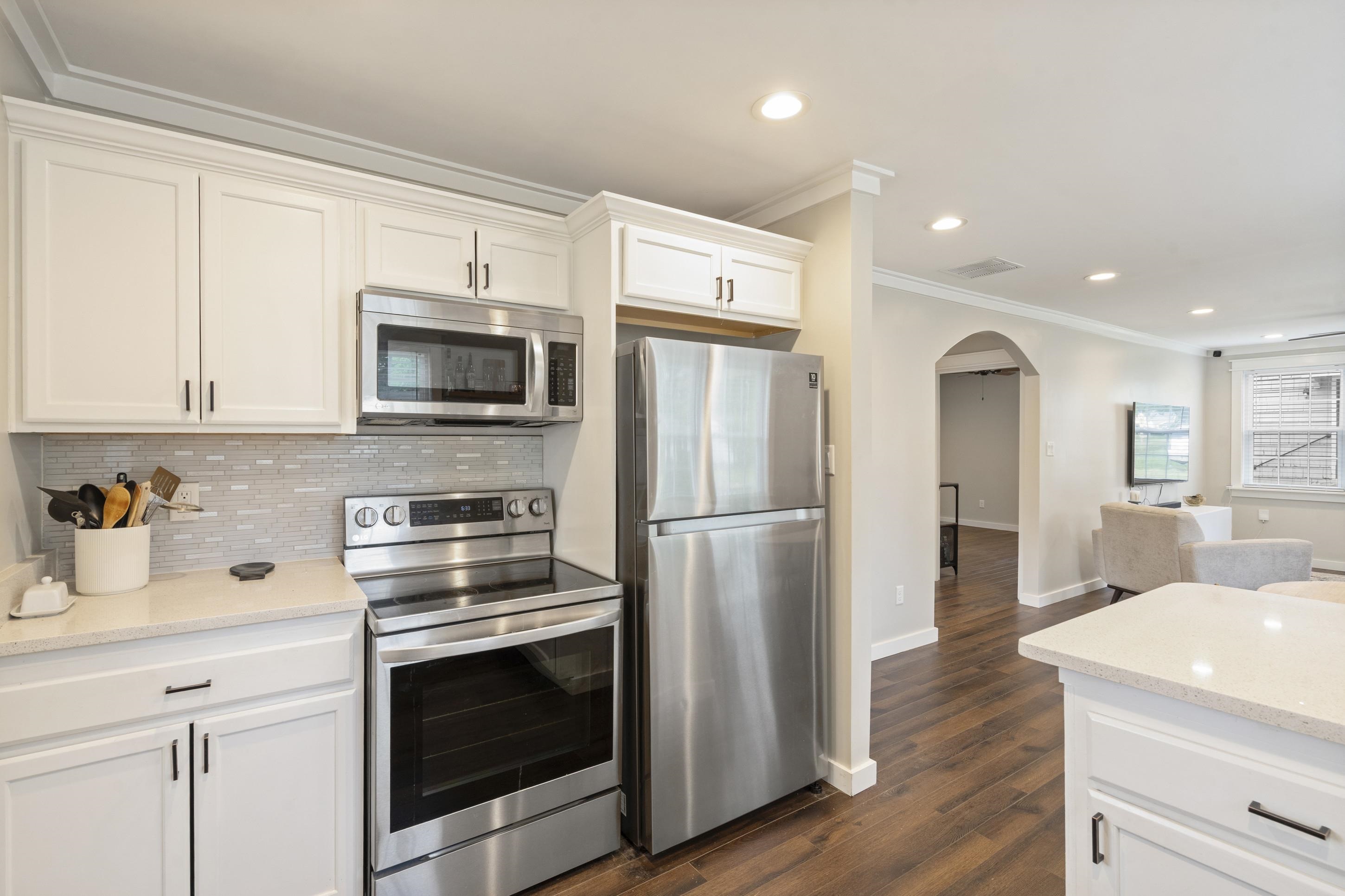 4370 Given Avenue Memphis, TN 38122 - Photo 3 of 30 Kitchen featuring white cabinetry with dark hardware, a mosaic tile backsplash, stainless steel appliances, and light-toned countertops