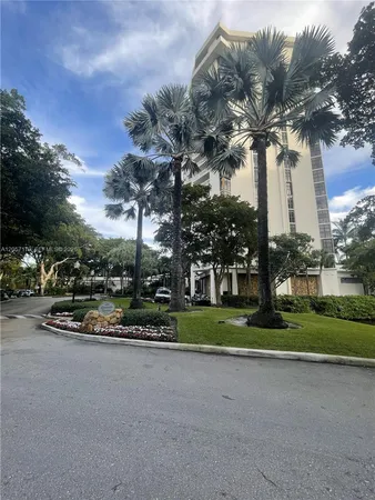 a view of a white house next to a road and large trees
