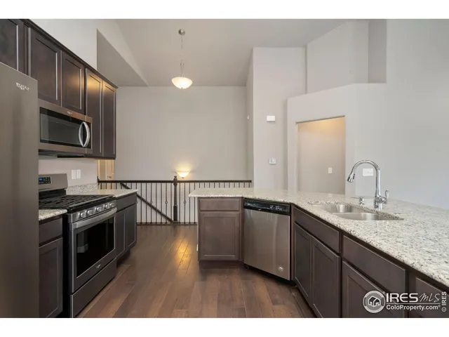 a kitchen with stainless steel appliances granite countertop a sink dishwasher a stove and a microwave oven with wooden floor