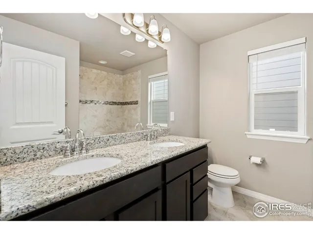a bathroom with a granite countertop sink a toilet and a mirror