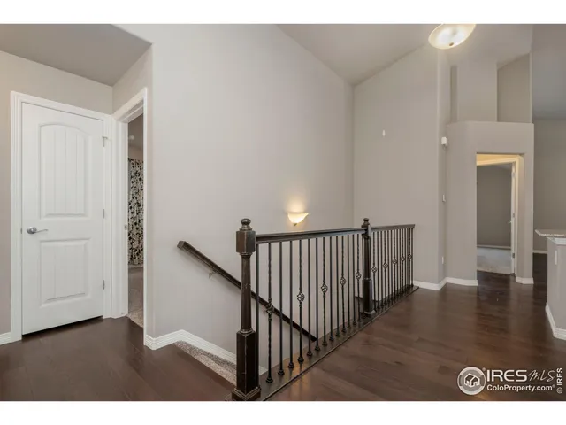 a view of a hallway with wooden floor and stairs