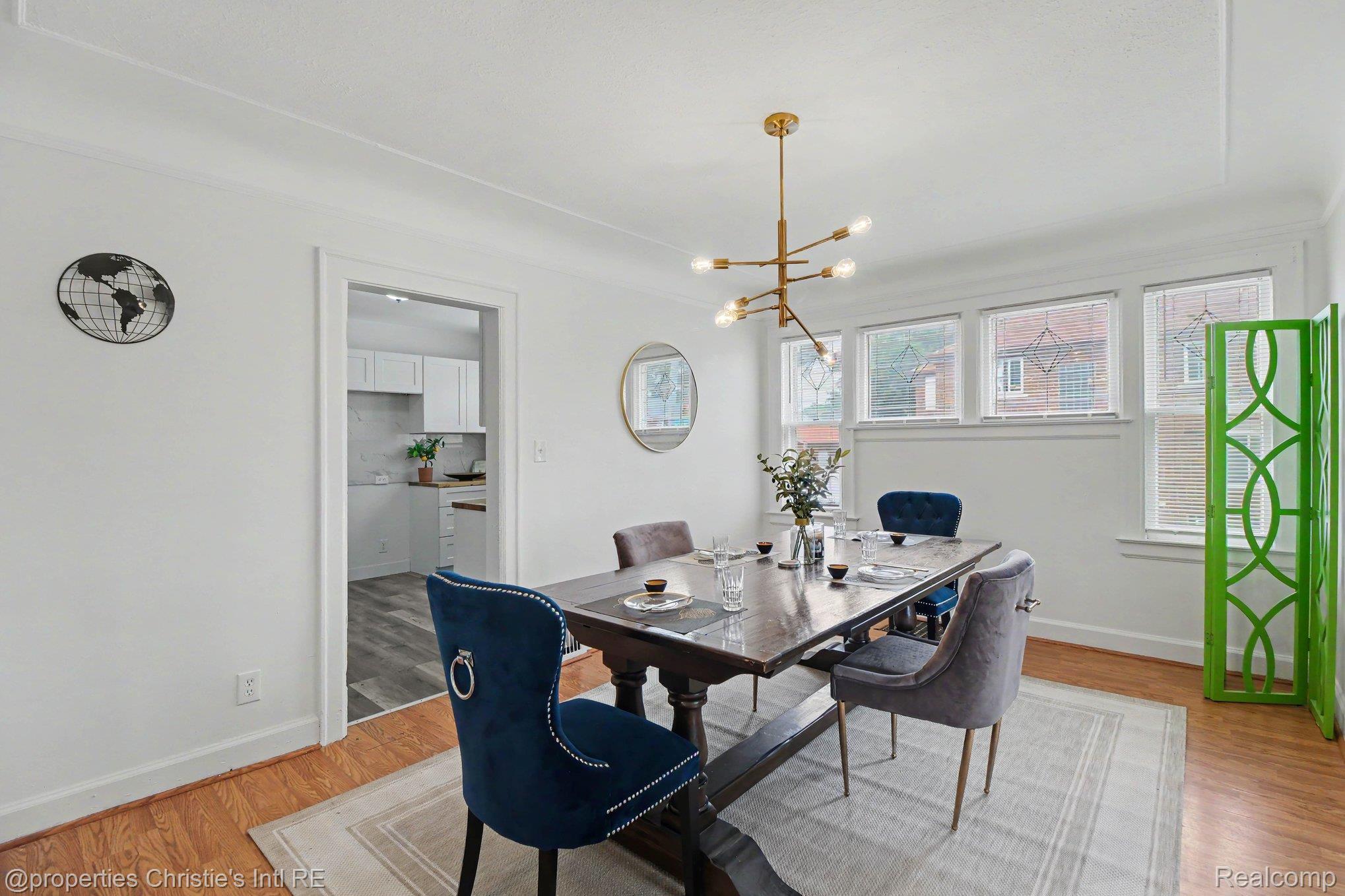 18315 Prairie Street Detroit, MI 48221 - Photo 4 of 16 Spacious room featuring wood-finish flooring, white baseboards, and a modern gold-toned chandelier