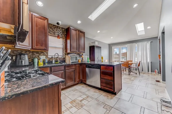 a kitchen with stainless steel appliances granite countertop a stove top oven a sink a counter space and cabinets