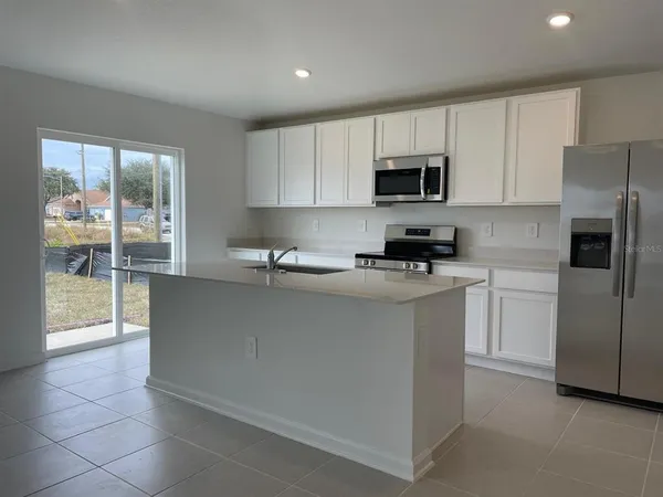 a kitchen with granite countertop a refrigerator and a stove top oven