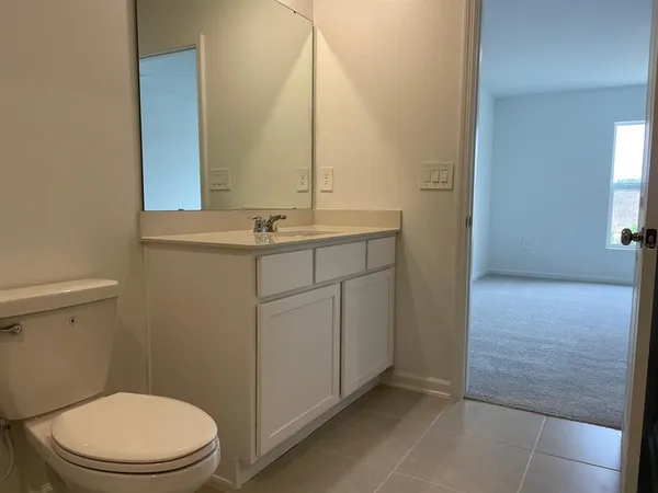a bathroom with a granite countertop sink a toilet and a mirror
