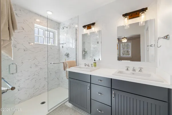 a bathroom with a double vanity sink mirror and shower