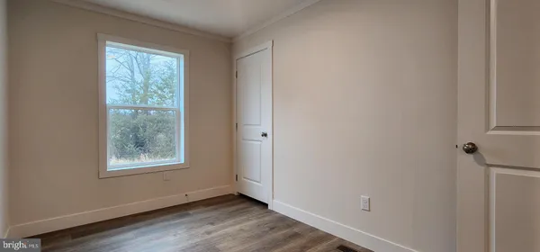 a view of an empty room with window and wooden floor