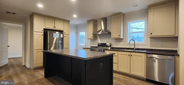 a kitchen with a sink dishwasher a refrigerator and cabinets with wooden floor