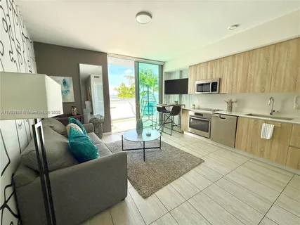 a living room with stainless steel appliances furniture and a kitchen view