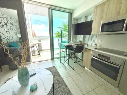 a living room with furniture a flat screen tv and floor to ceiling window