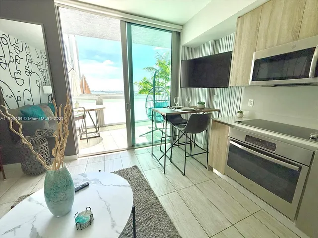 a living room with stainless steel appliances kitchen island granite countertop a couch a dining table and chairs