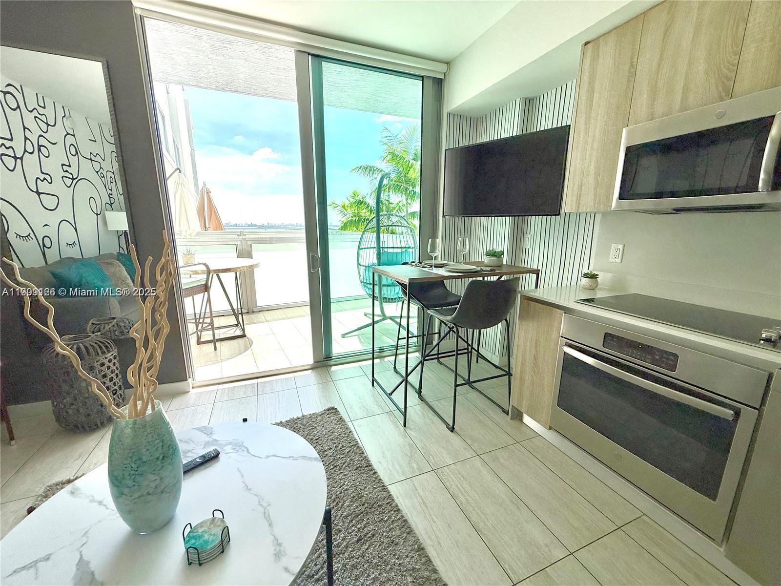 3900 Biscayne Boulevard, Unit N723 Miami, FL 33137 - Photo 5 of 30 a living room with furniture a flat screen tv and floor to ceiling window