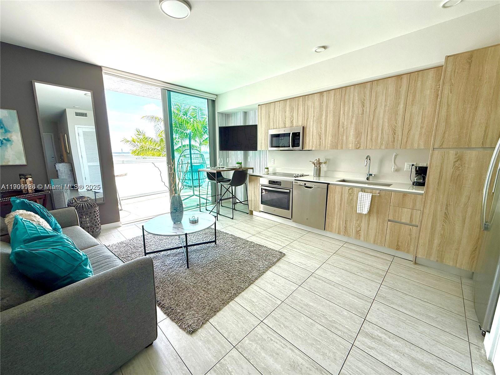 3900 Biscayne Boulevard, Unit N723 Miami, FL 33137 - Photo 6 of 30 a living room with stainless steel appliances kitchen island granite countertop a couch a dining table and chairs