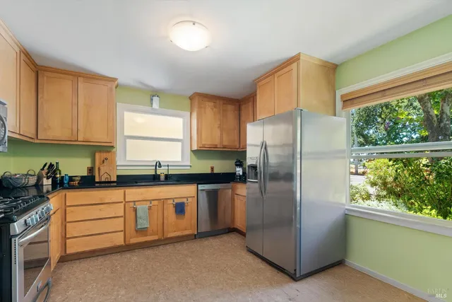 a kitchen with granite countertop white cabinets sink and stainless steel appliances