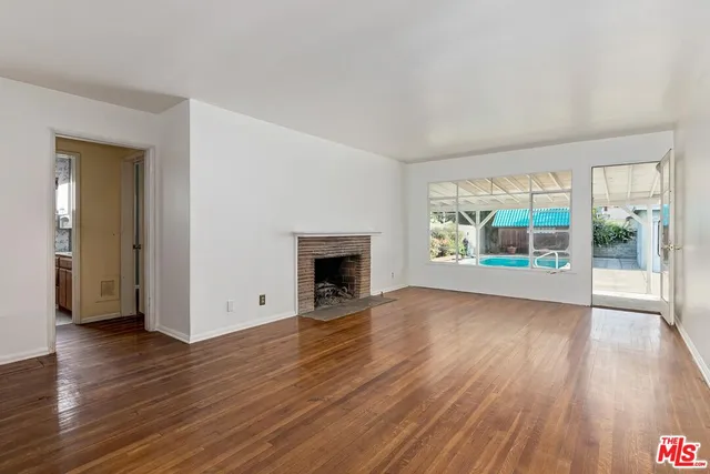 an empty room with wooden floor and fireplace