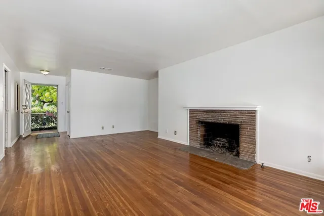a view of empty room with wooden floor and fireplace