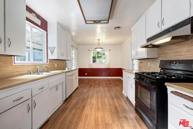 a large kitchen with a wooden floor and stainless steel appliances