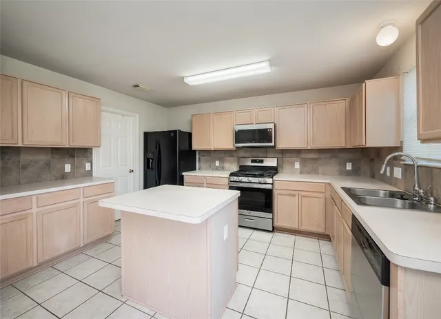a kitchen with a sink a stove top oven and white cabinets
