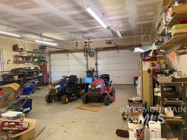 1095 County Road 70 Weiser, ID 83672 - Photo 30 of 44 Spacious garage featuring two overhead doors, concrete flooring, exposed ceiling beams, and built-in shelving