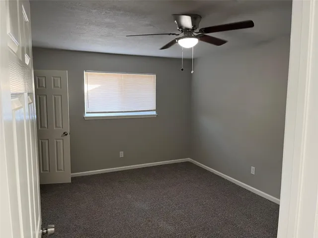 an empty room with a window and a fan
